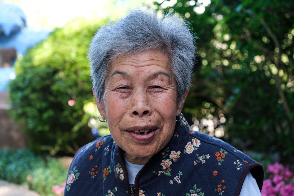 An elderly woman posing in a public park